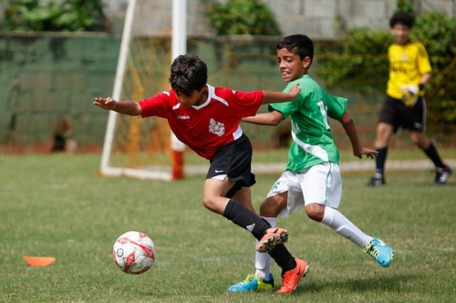  duas crianças jogando futebol